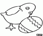 Pollito mirando un huevo de Pascua decorado